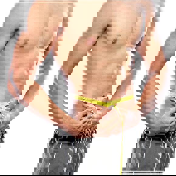 Fit man measuring waist with tape after contouring and liposuction