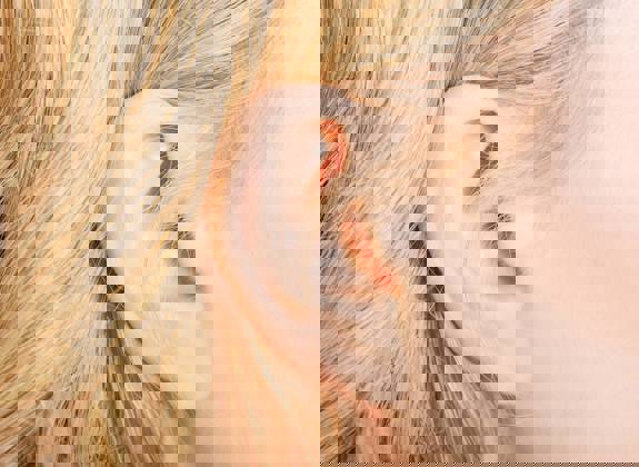 Close up of a woman's ear with blonde hair, showing normal outer ear structure and skin detail