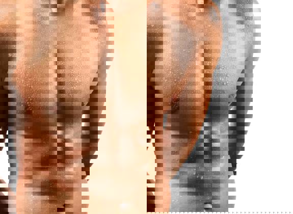 Close-up of fit male chest and abdomen after gynecomastia surgery showing natural, defined contour