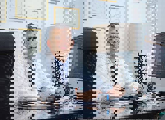 Dr Ioannis Liapakis in his clinic office with credentials displayed on wall