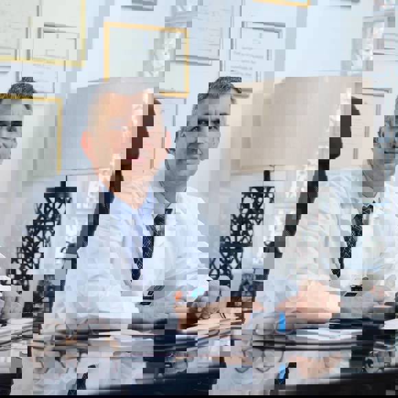 Dr Ioannis Liapakis in his clinic office with credentials displayed on wall