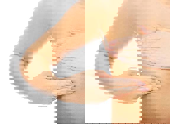 Close up of a woman performing a self breast examination with hands gently checking the breast area