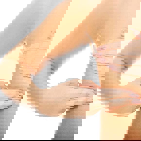 Close up of a woman performing a self breast examination with hands gently checking the breast area