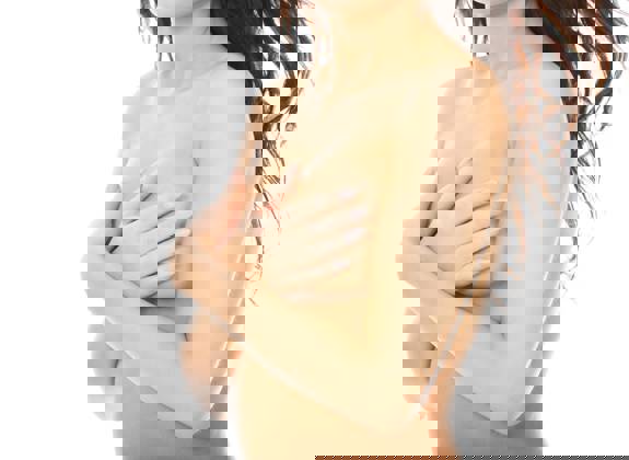 Close up of woman covering her chest with her hands, symbolizing breast health and self-examination awareness